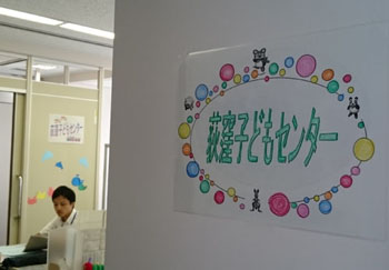 写真：柱に貼られた紙に「荻窪子どもセンター」の文字。動物のイラストとさまざまな色・大きさの丸で周りを囲っている